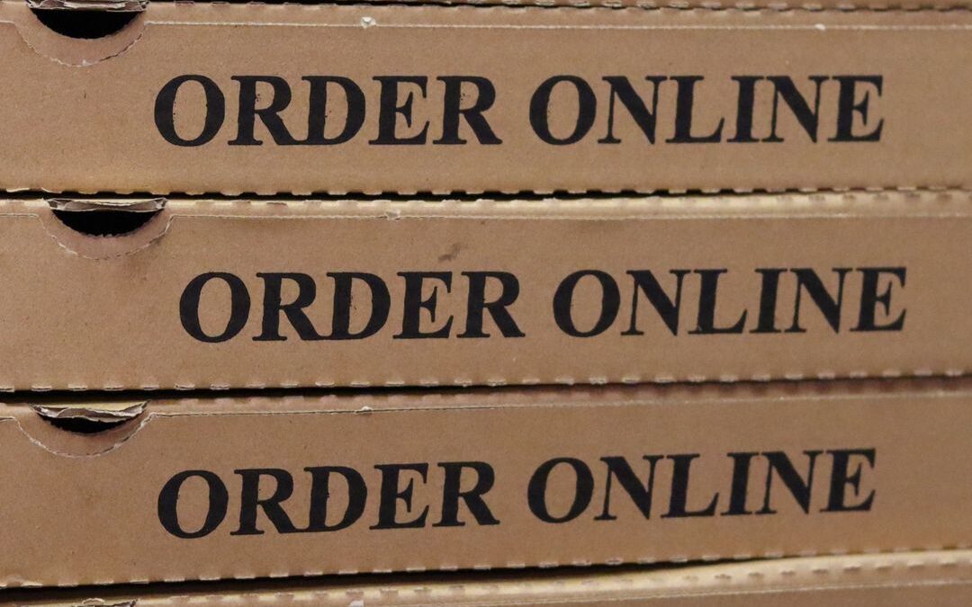People enjoying pizza and drinks at Stuft Pizza Bar & Grill in La Quinta during an NFL Sunday game, with multiple screens showing sports.